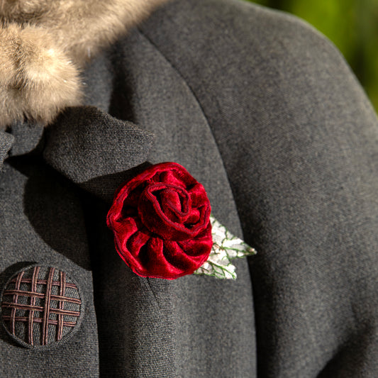 Red rose brooch on a gray coat with a blurred background